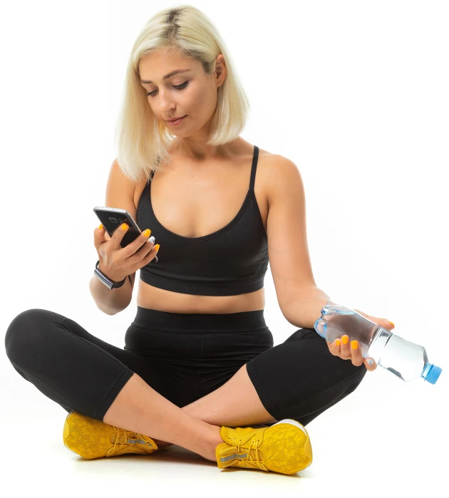 Woman in workout clothes checking her phone with a water bottle in hand